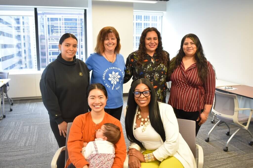 Miembros del grupo de discusión de padres del HFA posan juntos para una foto, 4 de pie y 2 sentados, uno con un bebé en brazos.