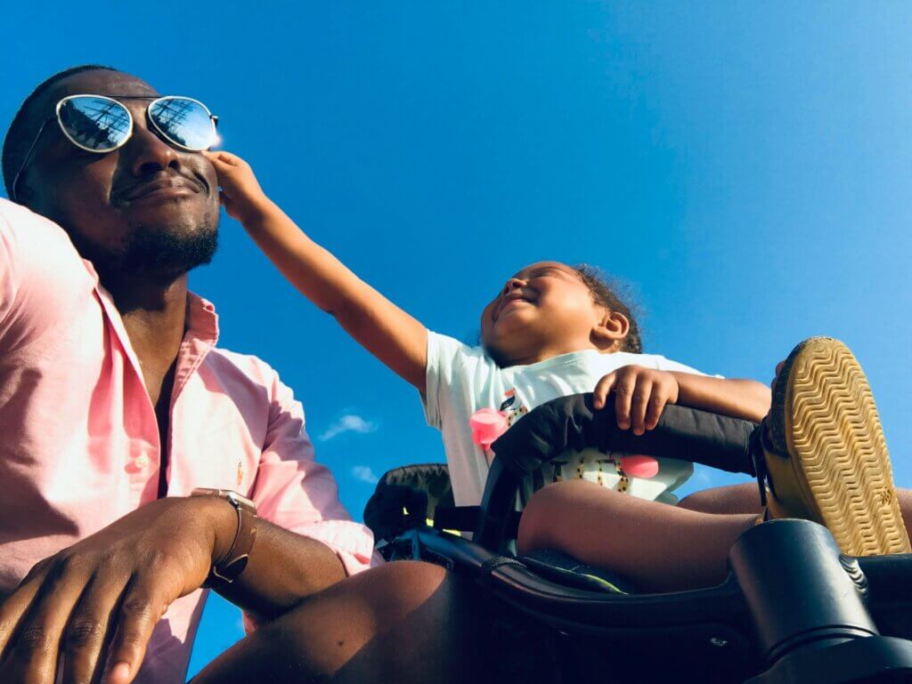 Child reaches out to touch his father's face and sunglasses