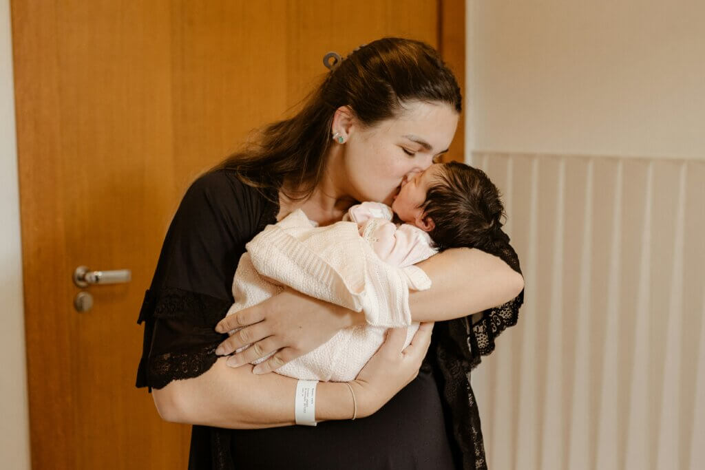 Mom snuggles and kisses a newborn baby