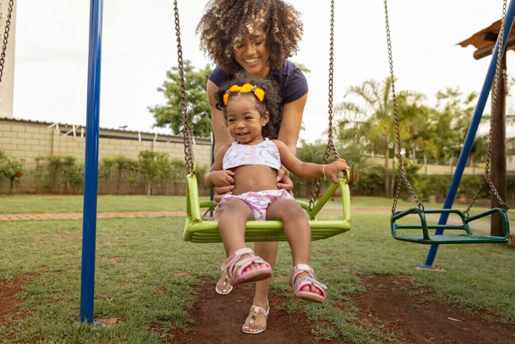 Mom pushes daughter on the swing