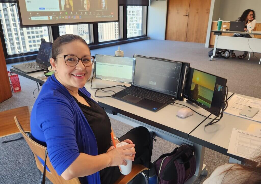 Lenny Rivota sits at her laptop with multiple screens