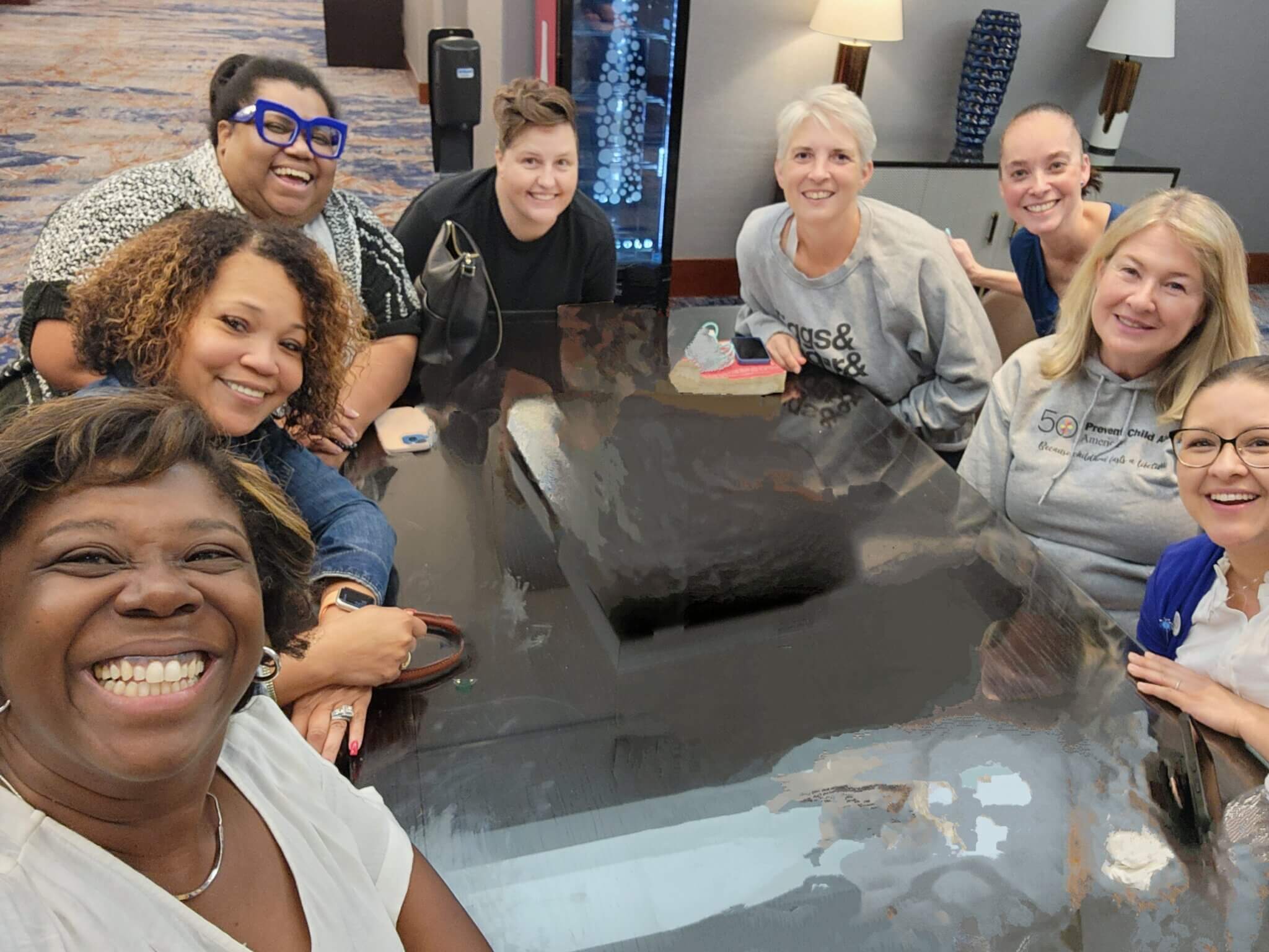 Staff sit around a table, smiling towards the camera